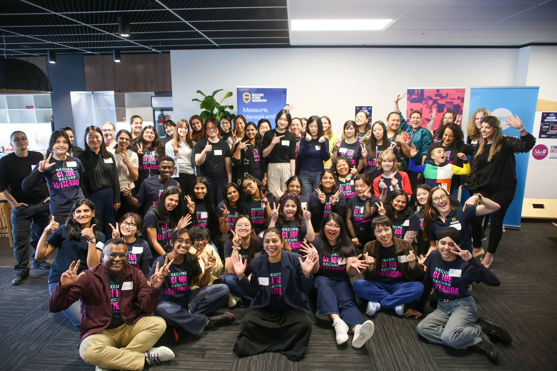 Large group of She Sharp community members gathered together at a technology conference, smiling for a group photo.