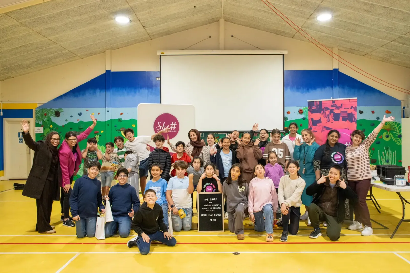 Workshop participants and SheSharp facilitators gather for a group photo with the SheSharp sign at the Youth Tech Series AI & Electronics Workshop