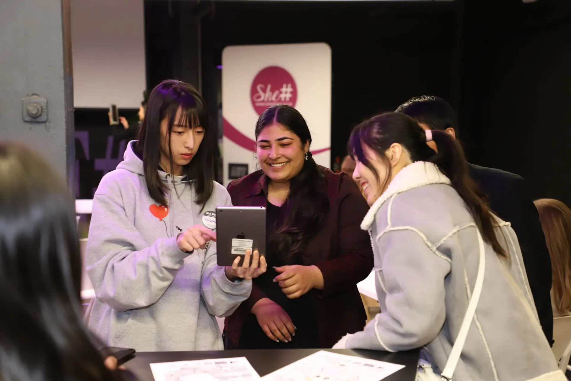 A small group looking at a tablet together during a She Sharp mentoring moment.