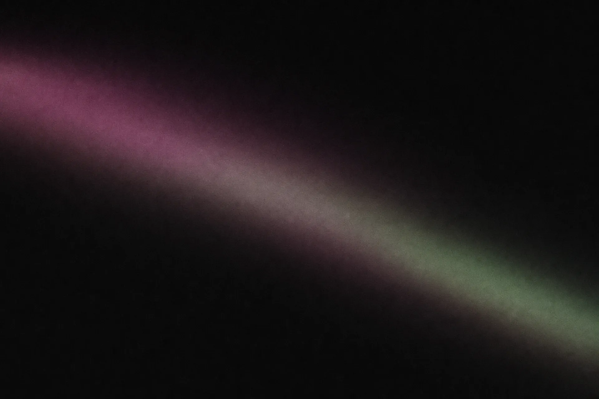 A sweep of magenta and pale green light across a near-black field, like an aurora seen through frosted glass.
